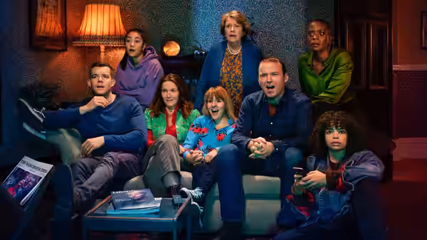 A family sits in a living room reacting with shock