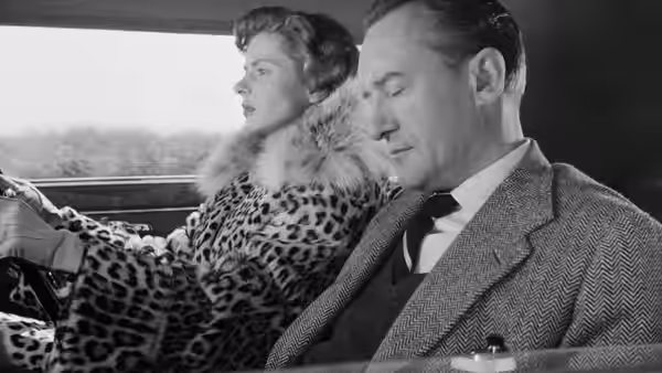 Katherine Joyce (Ingrid Bergman) and Alex Joyce (George Sanders) sit together in a car