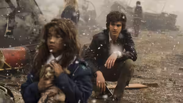Eddie Dunford (Andrew Garfield) sitting with a young girl amid snowy rubble