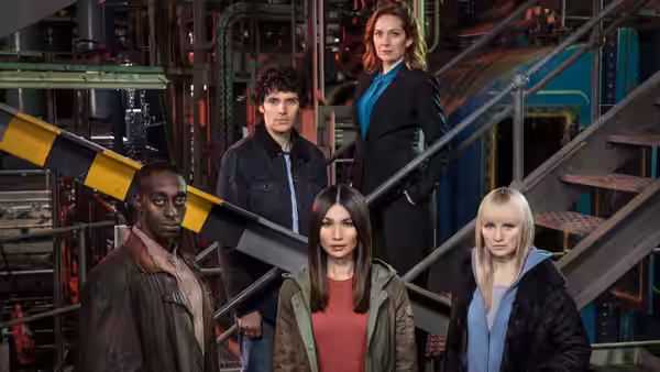 Five people standing on metal stairs in an industrial facility