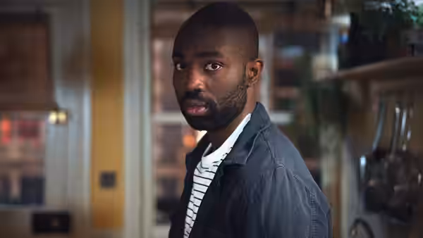 Paapa Essiedu as George glances over his shoulder in a kitchen