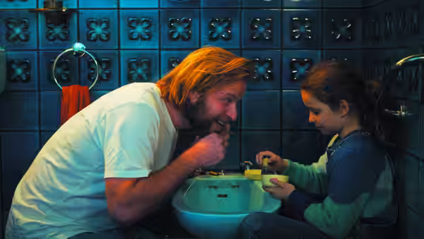 A father and daughter brush their teeth together at the bathroom sink