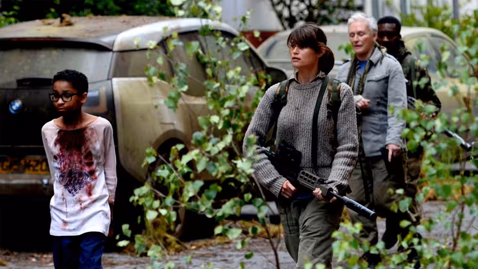 Melanie walks through overgrown streets as Helen carries a rifle nearby