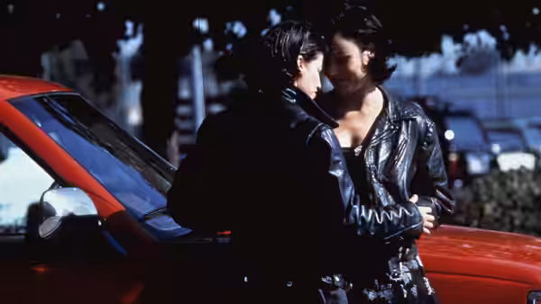 Corky (Gina Gershon) and Violet (Jennifer Tilly) embracing beside a red car