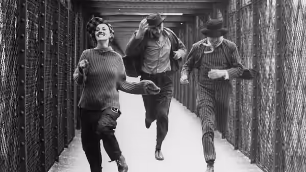 Catherine and two men run through a long corridor