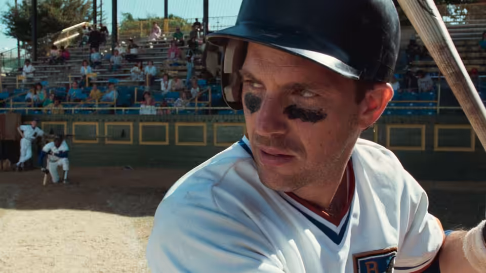 Crash Davis (Kevin Costner) holding a bat on the baseball field