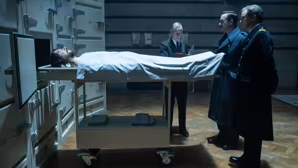 British officers examine a body on a trolley in a morgue