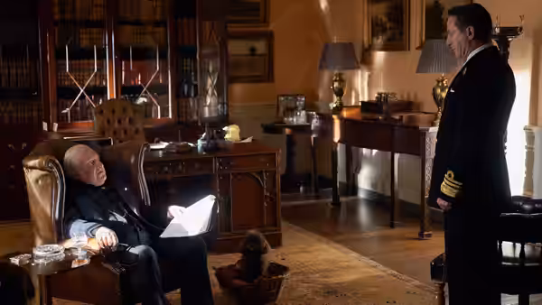 Winston Churchill (Simon Russell Beale) sits with papers as a naval officer stands before him
