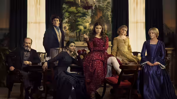 Six people in Victorian dress gathered in an ornate parlor
