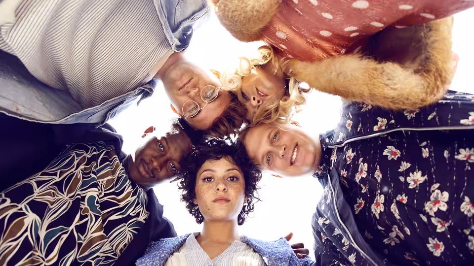 Five friends clustered together looking down at the camera from above