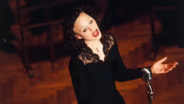 Edith Piaf (Marion Cotillard) sings beside a microphone in a black lace dress