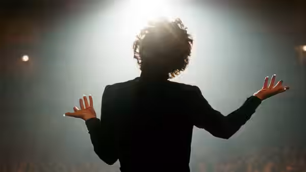A singer stands onstage with her arms spread toward the audience