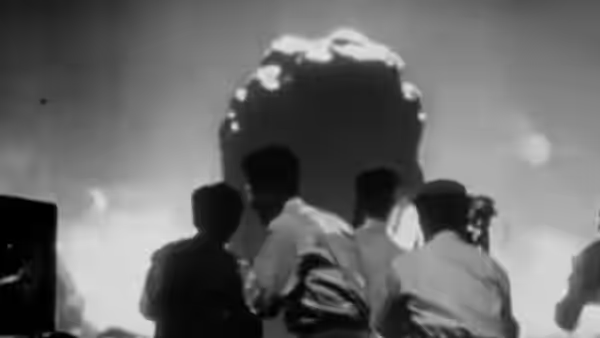 Men watching a large fiery explosion from behind