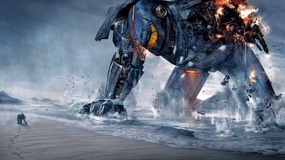 A large blue mech wades through ocean waves with sparks and fire erupting from its frame