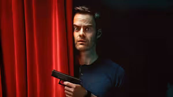 Barry Berkman (Bill Hader) peers from behind a red curtain holding a gun
