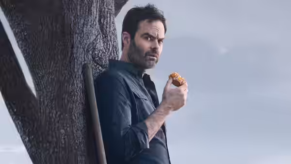 Barry Berkman (Bill Hader) leans on a tree eating a donut