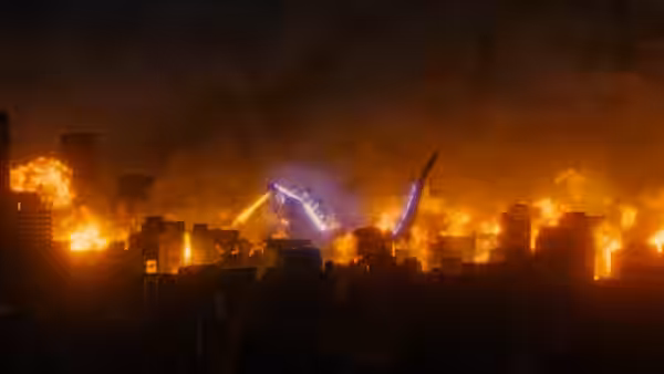Godzilla’s purple beam streaks across a burning city skyline