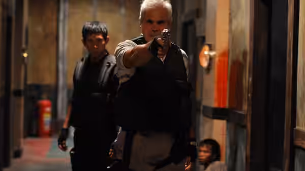 older officer aims handgun forward in a narrow hallway