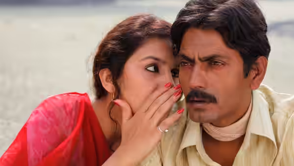 woman in red sari whispering into a mans ear by the water