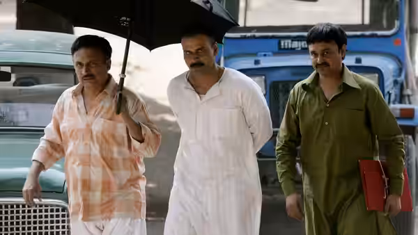 three men walking outdoors one holding a black umbrella near parked vehicles