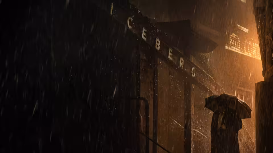 a figure with an umbrella stands in heavy rain outside the Iceberg building