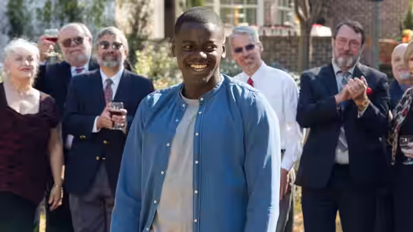 Chris (Daniel Kaluuya) smiling before clapping guests at an outdoor gathering