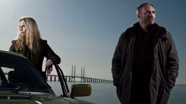 Saga Norén (Sofia Helin) leans on a car beside Martin Rohde (Kim Bodnia) near a bridge