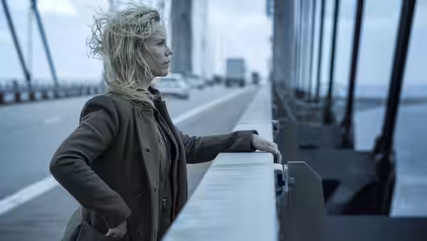 Saga Norén (Sofia Helin) stands on a bridge with windblown hair overlooking vehicles and water