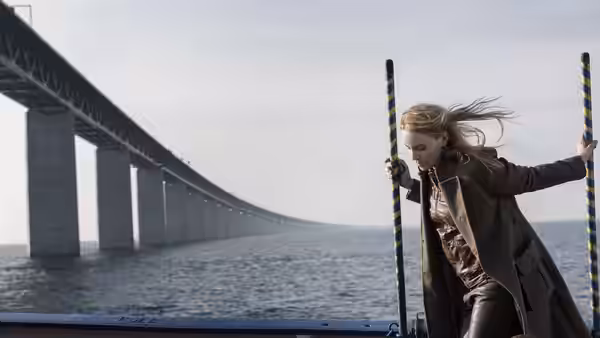 Saga Norén (Sofia Helin) grips striped poles on a bridge over the sea as wind blows her hair
