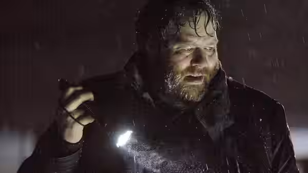 Andri (Ólafur Darri Ólafsson) holds a flashlight in heavy rain at night