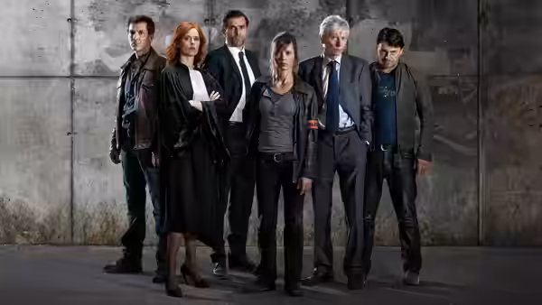 Six people stand in line against large concrete wall