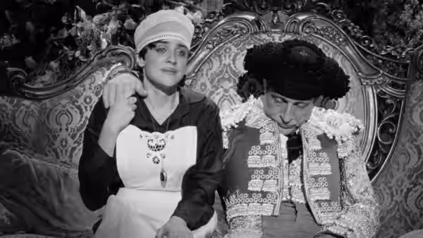 A maid sits beside a slumped matador on an ornate sofa