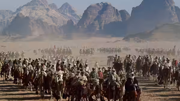 A large caravan of armed men riding camels through the desert