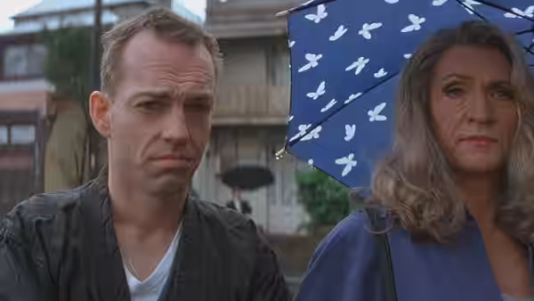 Man and gray-haired person holding a blue umbrella on a street