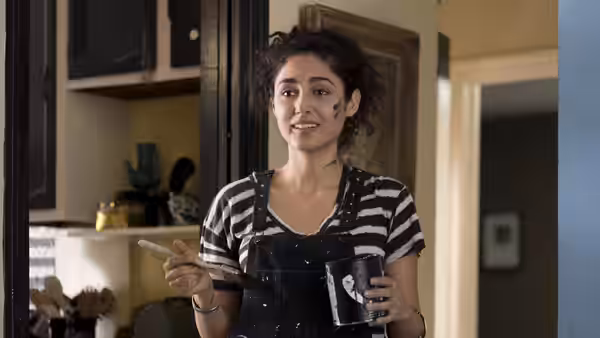Laura (Golshifteh Farahani) smiles while holding a paintbrush and cup in the kitchen doorway
