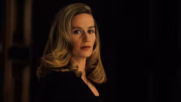 a blonde woman looking aside in a dimly lit interior
