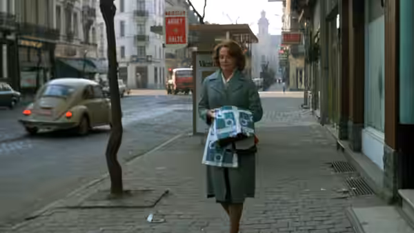 Jeanne Dielman (Delphine Seyrig) carries groceries along a city sidewalk