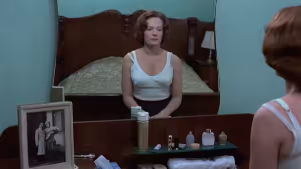 Jeanne Dielman (Delphine Seyrig) sits before her bedroom mirror