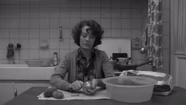 Jeanne Dielman (Delphine Seyrig) peels potatoes at the kitchen table