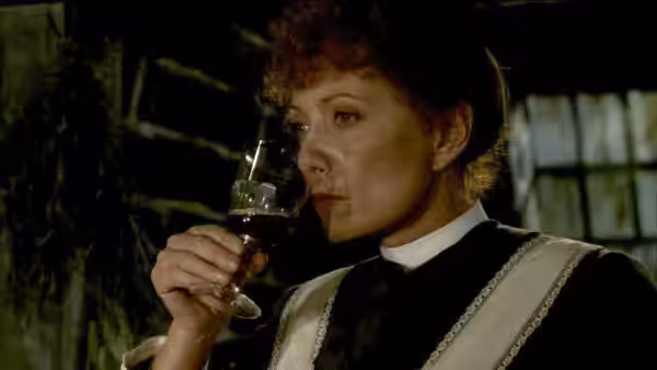 Babette (Stéphane Audran) raises a glass of wine to her lips indoors