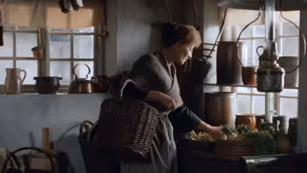 Babette (Stéphane Audran) gathers ingredients in the kitchen beside pots and baskets