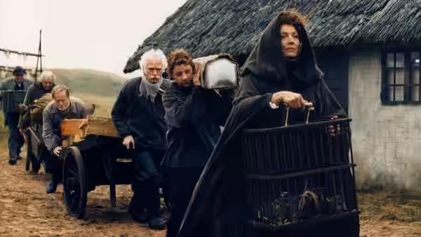 A hooded woman carries a wicker cage as villagers haul a cart along a country path