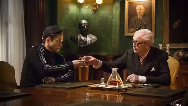 Eggsy (Taron Egerton) meets Arthur (Michael Caine) across a desk in the Kingsman office