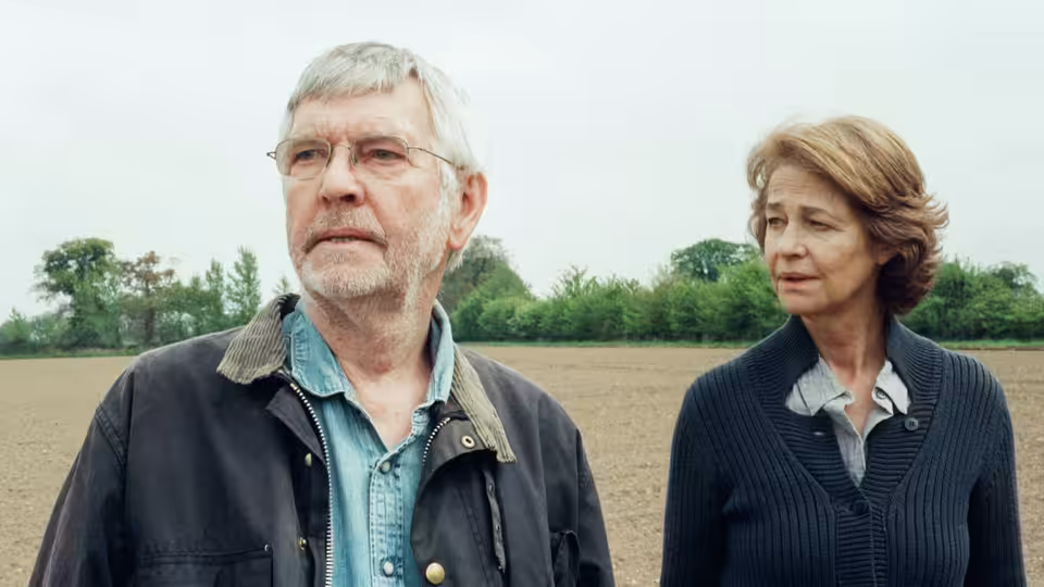Geoff Mercer (Tom Courtenay) and Kate Mercer (Charlotte Rampling) standing in a ploughed field