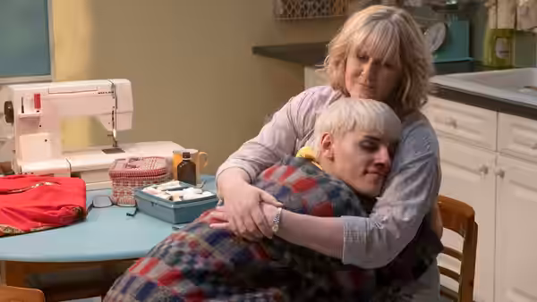 Margaret New (Sarah Lancashire) embraces Jamie in their kitchen