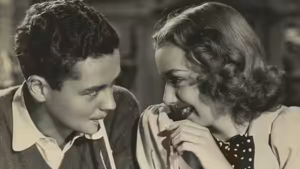 A young man and woman lean close as she holds a cup