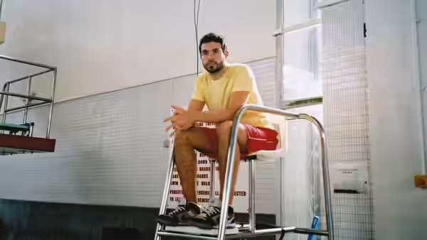 Man sitting on a lifeguard chair inside a tiled room