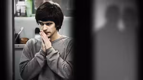 Ben Coulter (Ben Whishaw) stands indoors with his hands clasped beneath his chin