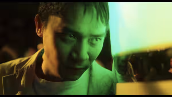 Poet (Tony Leung) peers past a green-lit pane