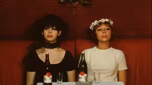 Two women in hats sit at a table with beer bottles and glasses